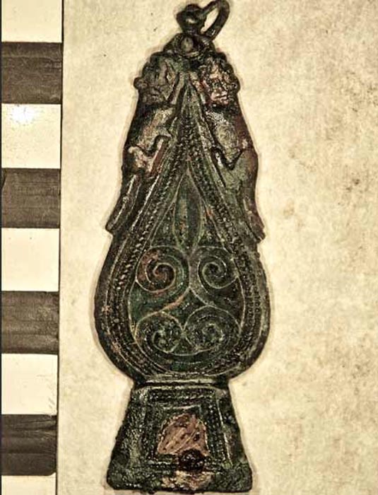 Crouching dogs can be seen on either side of the strap end.