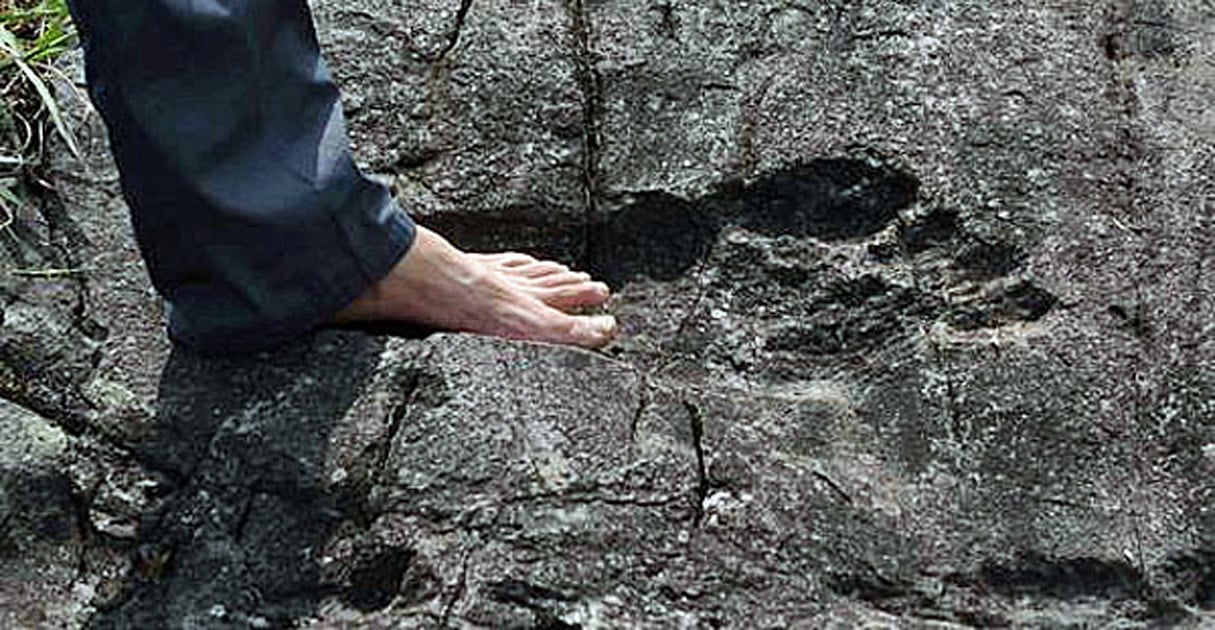A man stands in what appears to be a giant footprint in bedrock in Pingyin China