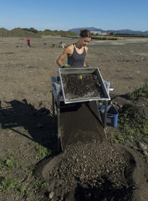 Synne H. Rostad operates a standing sieve to sift out smaller bones and objects from the dirt.