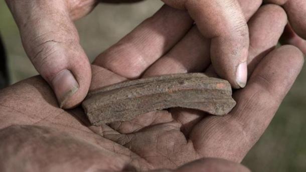 Ryan Smith (trench supervisor) holding a Phoenician red slip water from Western Turkey.