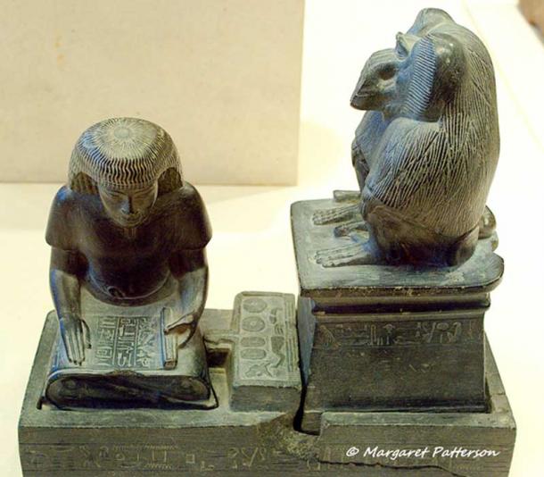 Scribe Nebmerutef is portrayed                  under the attentive gaze of the god Thoth, patron of                  writing. He is engrossed in reading a document, seated                  cross-legged on the ground, with his torso leaning                  slightly forward, and his right hand resting on the                  papyrus. Above him, the baboon sacred to Thoth is seated                  on a pedestal. New Kingdom. Louvre Museum, Paris.
