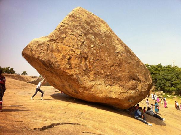 A person trying to move the boulder 