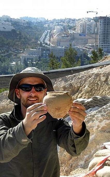 Alex Wigman, an Israel Antiquities Authority archaeologist, holds a small jar from the Canaanite tomb in Jerusalem. (Shua Kisilevitz, Israel Antiquities Authority)
