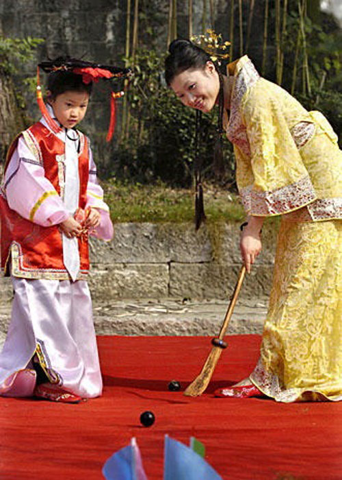 A Chinese boy and woman in ancient style dress playing Chuiwan golf. (China Radio International)