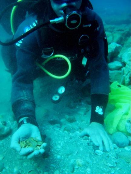 Diver holding a handful of the newly-discovered coins in Israel. 