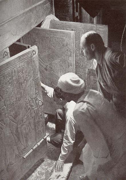 Howard Carter (squatting), Arthur Callender and an Egyptian workman, looking into the opened shrines enclosing Tutankhamun's sarcophagus in 1924. (Public domain)