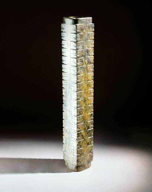 Large Chinese cong of opaque dark olive green jade. Liangzhu culture, China (c. 3300 -2200 BC). Among Neolithic jades, the cong displays the most complex form: a cylindrical tube encased in a square prism that gently tapers from top to bottom. Simple masks with circular eyes and bar-shaped mouths decorate the corners. Enigmatic in function and meaning, the cong probably signified wealth and social status. In a tomb found at Sidun, Jiangsu Province, numerous cong lay in a circle around the dead, suggesting that they also served a religious or ritual purpose. (CC by SA 4.0 / Trustees of the British Museum)