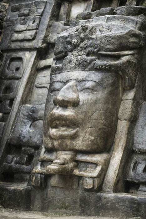 This Olmec style stone face on the Lamanai Mayan temple in Belize is almost identical to the later Maya temple shown in the main image at the top of this article. (Wollwerth Imagery / Adobe Stock)