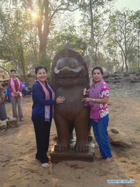 People posing for photos with a newly discovered 7ft (2m) tall lion statue in Banteay Meanchey Province. (Photo released by Cambodia's Culture Ministry / Xinhuanet)
