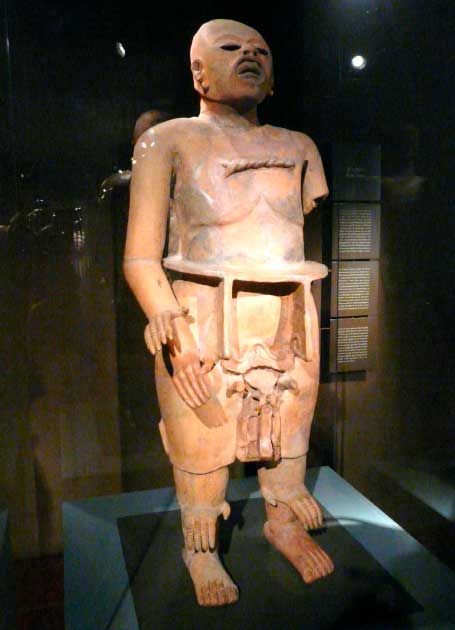 Statue of Xipe Totec, the flayed-skin god (Bkwillwm / CC BY SA 3.0).  Xipe Totec is represented wearing flayed human skin, usually with the skin of the hands falling loose from the wrists. At the annual festival of Xipe Totec slaves or captives were sacrificed and priests wore the flayed skin of the victims with the fresh blood still dripping.