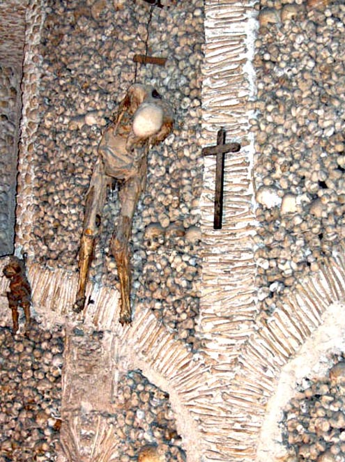 Deux cadavres humains, correspondant à un homme adulte et à un jeune enfant, travaillent la chaîne d'un mur de la chapelle des os.