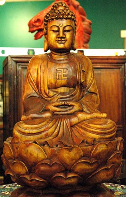 Wooden Buddha statue with gamadian (swastika). (CC BY 2.0)