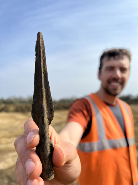 El arqueólogo Joe Price sosteniendo la punta de lanza de la Edad del Bronce que descubrieron recientemente. (Arqueología de Cotswolds)