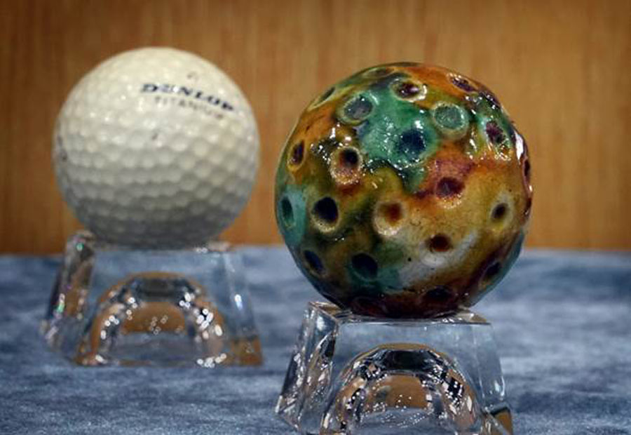 A ceramic Chuiwan golf ball (R) and a modern golf ball (L) displayed in an art gallery at Pingdingshan University, Henan Province, China.	Source: Li An / Xinhua