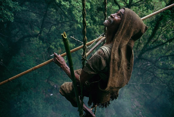 A honey hunter hangs from a hand-made rope ladder. (Photo credit: Eric Valli) 