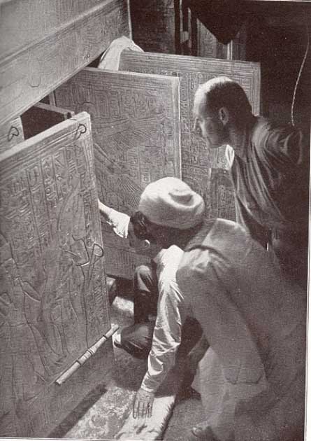 Howard Carter (arrodillado), Arthur Callender y un trabajador egipcio en la cámara funeraria, mirando a través de las puertas abiertas de los cuatro santuarios dorados hacia el sarcófago de cuarcita de Tutankamón (dominio público)