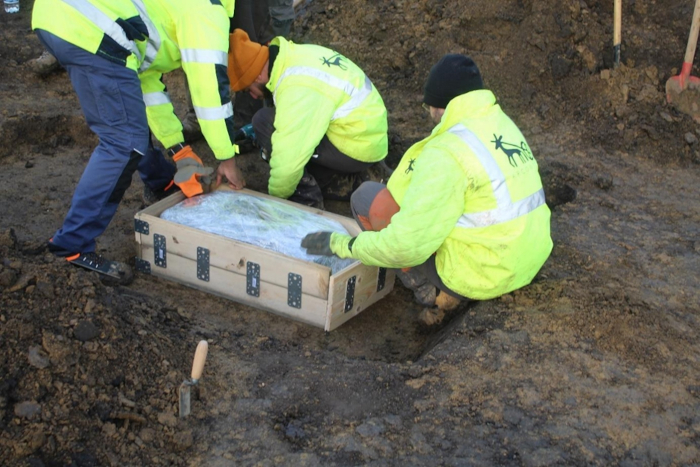 Researchers with a chest full of archaeological finds at the site. 