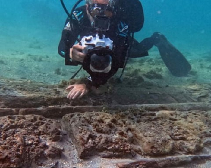 Film-maker Chris Atkins with the charred wooden hull of an 18th-century shipwreck. 