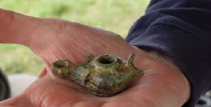 Archaeologist holdinga small Roman lamp.