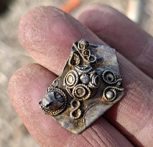 A fragment of a silver brooch, found alongside the coins
