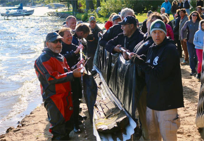 Volunteers removing ancient dugout canoe from lake.