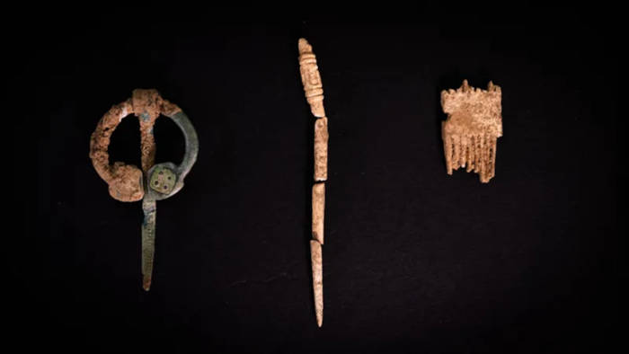 A copper brooch, a decorated bone pin and a comb carved from antler. 