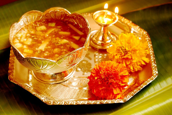Ugadi Pachadi served in a cup placed in a tray along with flowers and a diya