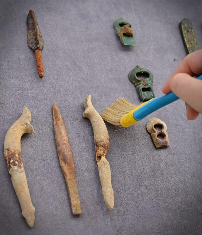 Archaeologists clean bone and metal artifacts recovered from the Baydala burial complex