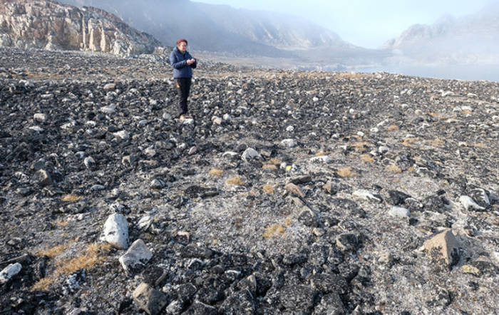 Study author near a tent ring of rocks in the rocky landscape.