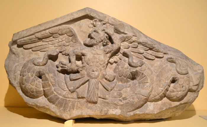 1st century BC pediment with relief-carving of a winged, snake-footed deity holding a lightning bolt