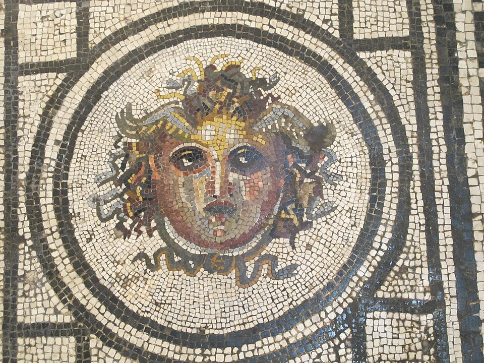 Mosaic showing makeup and blonde curls that are transforming into serpents