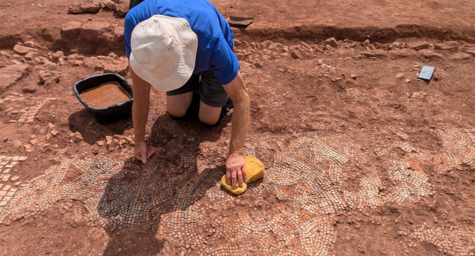 Archaeologist carefully cleaning the intricate Roman mosaic