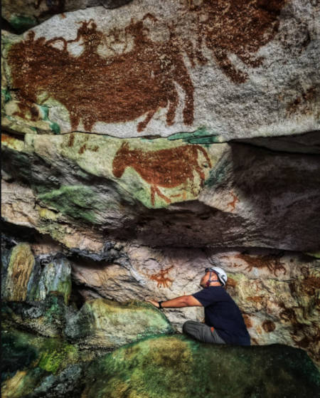 Dr Shinatria Adhityatama working in the cave by images of animals.