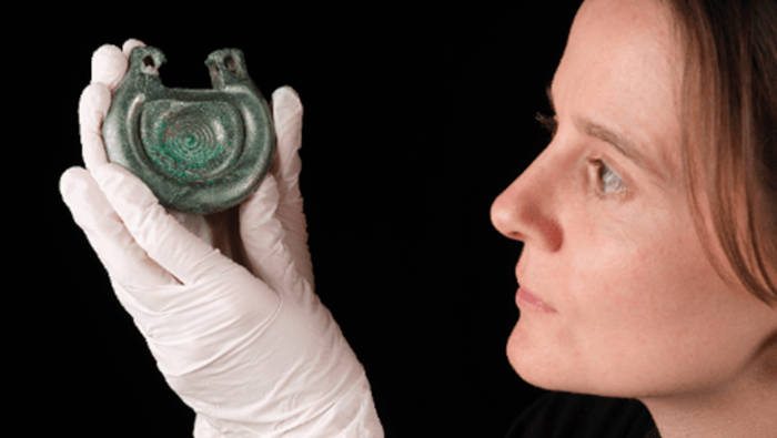 Archaeologist holding up an item from the hoard.