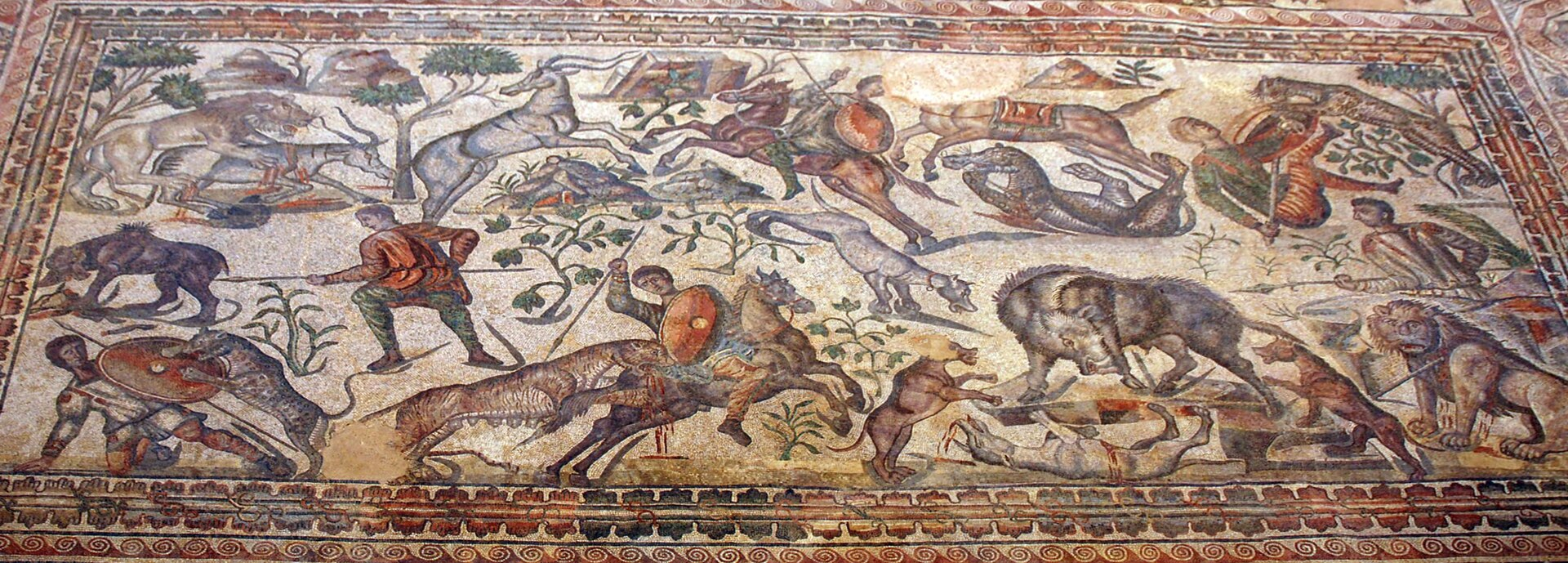 Roman mosaic showing a dramatic hunting scene (venatio) involving mounted hunters, wild animals, and hunting dogs