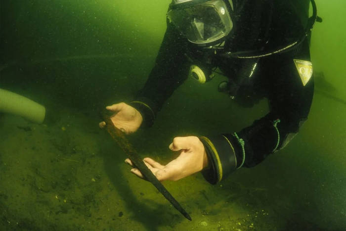 Archaeologist underwater with a spearhead.