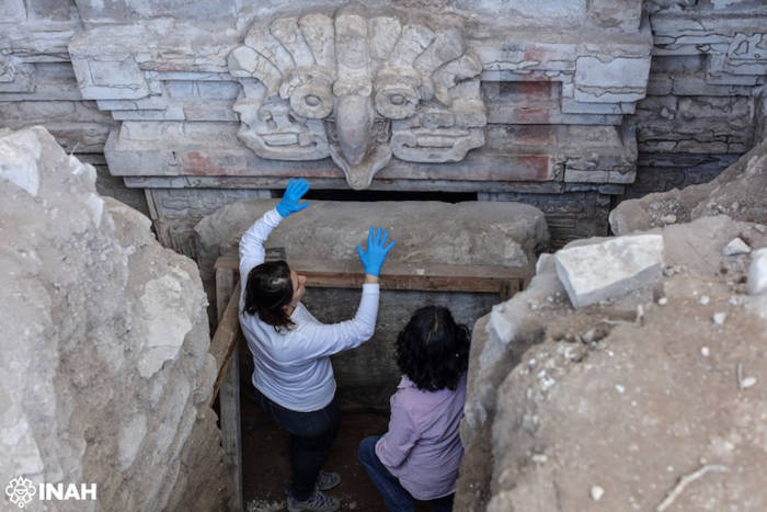 Researchers examining the owl and Zapotec face over the tomb entrance 