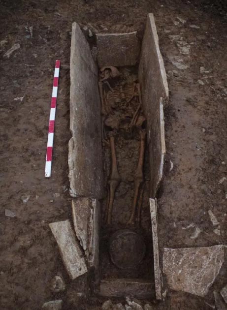 One of the skeletons in the stone coffin structure with a pot (at bottom of the shot) unearthed at the Roman burial site. (Wessex Archaeology)