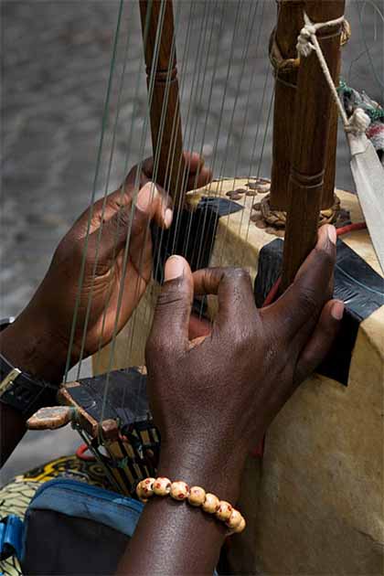 A griot tells stories through music. They are highly skilled in many instruments including the African kora (a stringed instrument) seen here. (© Jorge Royan /CC)