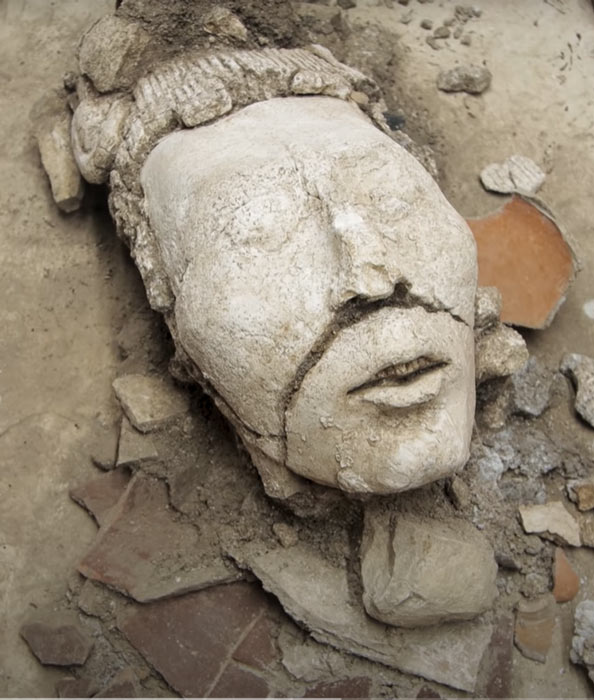 The stuccoed young corn god head as it was discovered in the stucco-walled pond while the INAH team was following a corridor between two rooms in the vast ruins of Palenque. (YouTube screenshot / INAH)