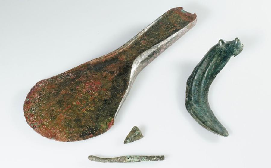 : A collection of Bronze Age objects found at the site, including the axe, dress pin, and sickle