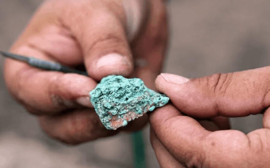 An excavator examines a malachite fragment from the 9,000-year-old Çayönü copper workshop.