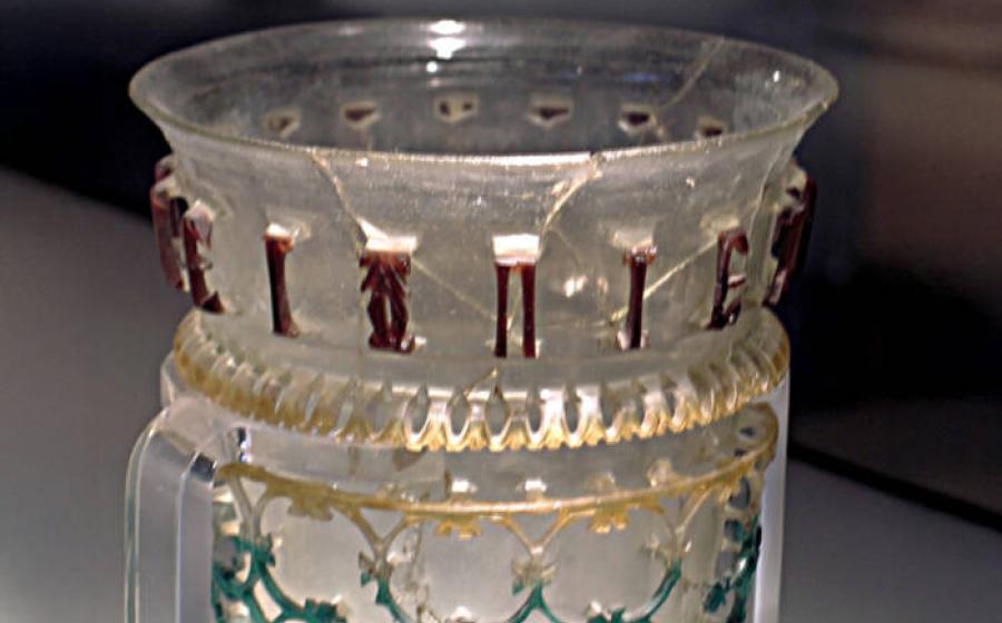 Glass openwork vessel from 300–350 AD with inscription and symbol.