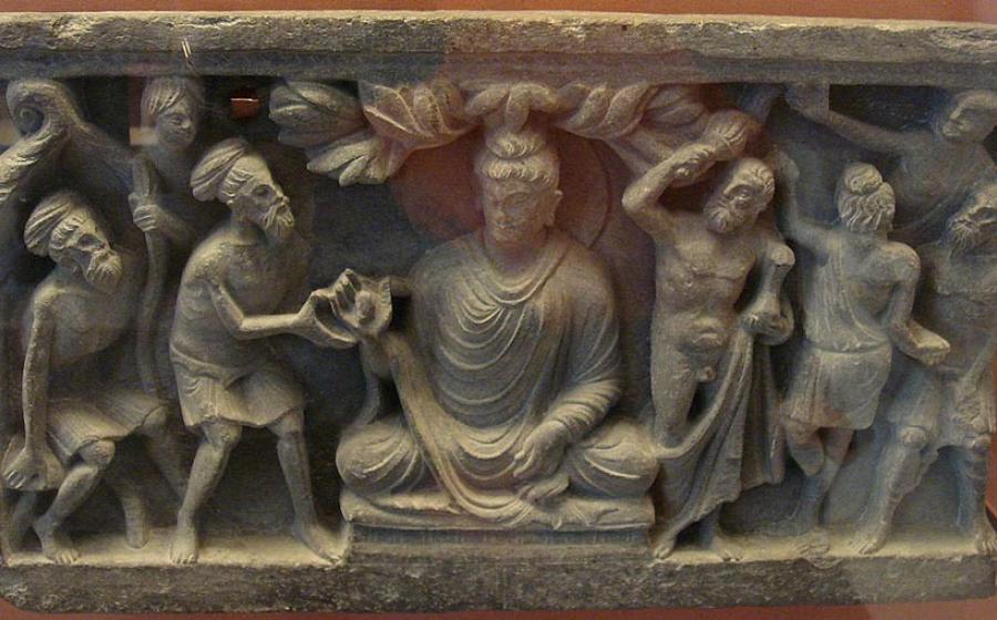 A Kushan empire (30–375 AD) frieze showing the Buddha flanked on the left by a Greek-inspired Vajrapani that clearly highlights the aesthetic nuances of Greek Buddhism.		Source: Goldsmelter / CC BY-SA 4.0