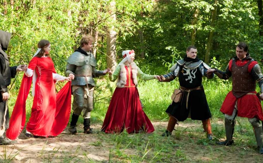 A group in traditional medieval attire engaged in a medieval circle dance.   Source: JackF /Adobe Stock                