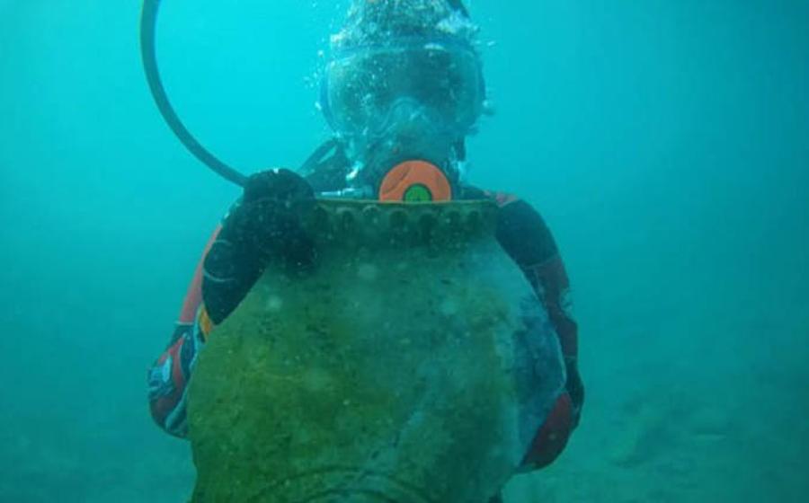 A marine archaeologist holding up an artifact under water in Lake Issyk-Kulin, Kyrgystan.