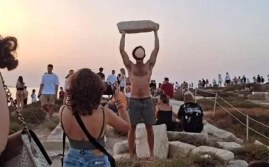 Tourist hold ancient stone aloft at Naxos, Greece.
