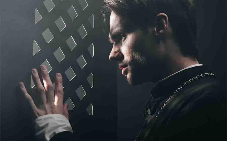 A young priest listens to confession. 