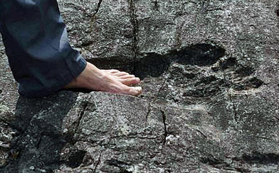 A man stands in what appears to be a giant footprint in bedrock in Pingyin China