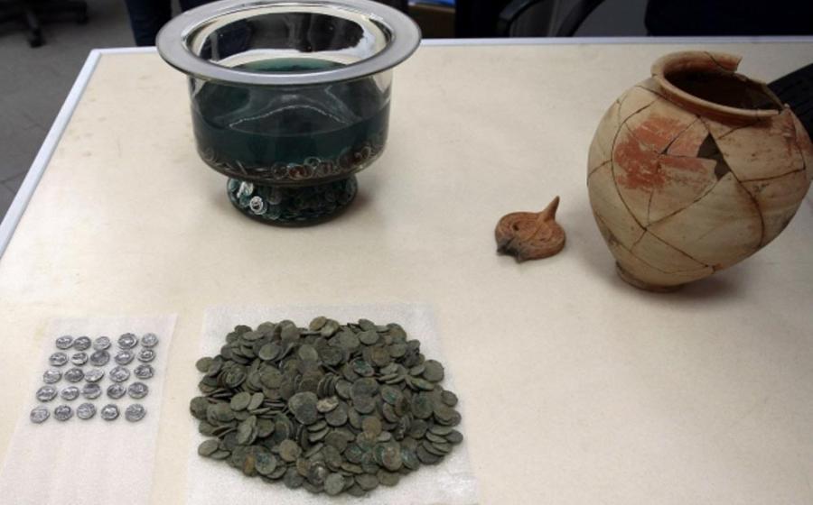 The ancient Roman coins, dating to the 1st century AD alongside the clay vessel in which they were found; the owner’s name is inscribed on the vessel. 